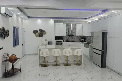 a kitchen with white cabinets and a counter with four stools at Bocachica house,apts,village in Jubey