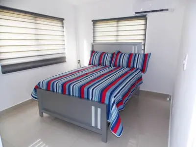 a bed with a striped blanket in a room at Cañaveral Del Mar 1 Quiet and extremally relaxing! in San Felipe de Puerto Plata