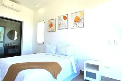 a white bedroom with a bed and some pictures on the wall at New 2 BR apt with swimming pool at playa bonita in Las Terrenas