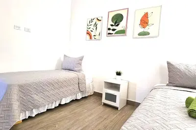 a white bedroom with two beds and a night stand at New 2 BR apt with swimming pool at playa bonita in Las Terrenas