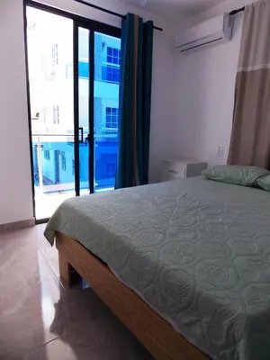 a bedroom with a bed and a large window at Residencial Victoria in Sampiño