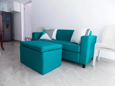a blue couch and a stool in a living room at Residencial Victoria in Sampiño
