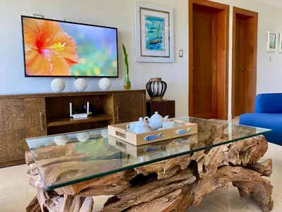a living room with a glass table and a tv at Blue View Beachfront Apartment with Ocean View in Sampiño