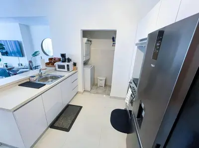 a kitchen with a stainless steel refrigerator and white cabinets at Modern City Condo El Millon in El Jobo de Mendoza