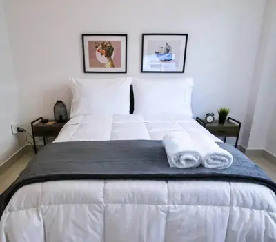 a large white bed with two folded towels on it at Modern City Condo El Millon in El Jobo de Mendoza