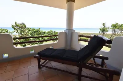 a chair on a porch with a view of the ocean at Bluefish Condo, Ocean Front, Sunrises, Pool, Hot Tub, Under New Management in Sosúa