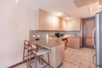 a kitchen with wooden cabinets and a island with chairs at Apartment nearby the beach at Portillo RAA in Las Terrenas