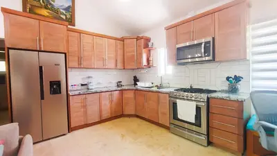 a kitchen with wooden cabinets and a stainless steel refrigerator at Brisa Atlántico - Secluded Beach in La Piña