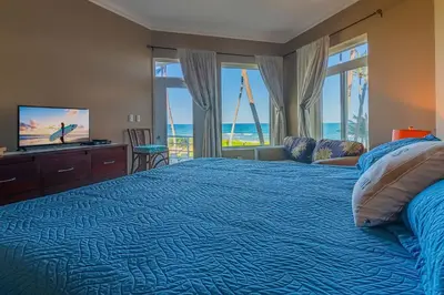 a bedroom with a blue bed with a view of the ocean at Truly Beachfront at Quiet Beach in Cabarete