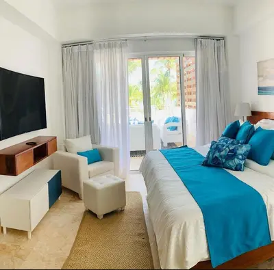 a bedroom with a large bed with blue sheets and a television at Luxury Penthouse Coson bay in Las Terrenas