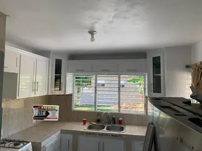 a kitchen with white cabinets and a sink and a window at Romeos Place in Las Coles