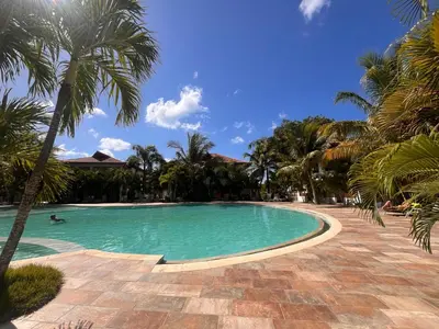 a swimming pool with palm trees in a resort at Residencial Paraiso C102 in Bayahibe