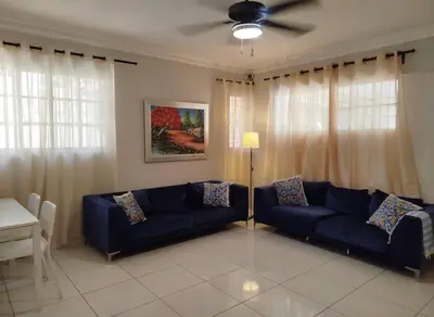 a living room with a blue couch and a ceiling fan at Apartamento próximo al centro médico HOMS in Hato Mayor