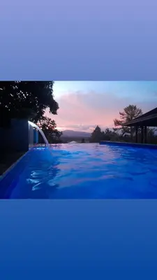 a blue swimming pool with a sunset in the background at Villabenedetta santo domingo in Varía