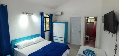 a bedroom with a blue and white bed and a tv at Charmant appartement cuisine 1 chambre AC Bonita in El Hoyo del Cacao