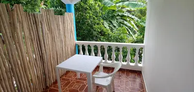 a white table and chair on a balcony with a fence at Charmant appartement cuisine 1 chambre AC Bonita in El Hoyo del Cacao