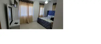 a small bedroom with a blue chair and curtains at Charming 2BR Apt Near Beach in Sabana Grande
