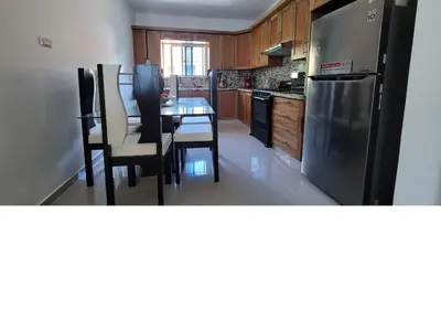 a kitchen with a table and a stainless steel refrigerator at Charming 2BR Apt Near Beach in Sabana Grande