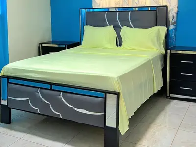 a bed with a black frame and yellow sheets at Villa Rosa in San Felipe de Puerto Plata