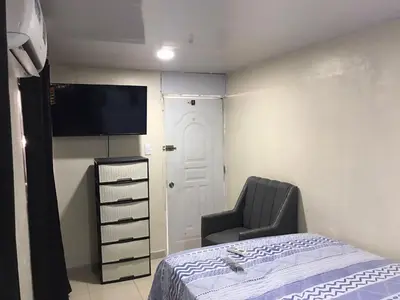 a bedroom with a bed and a chair and a flat screen tv at lugar comodo y barato in Santiago de los Caballeros
