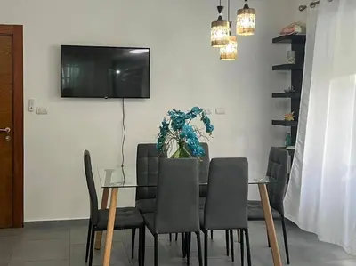 a dining room table with chairs and a television on a wall at A private cozy-beach apartment in Dominicus in La Laguna