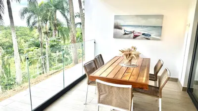 a dining room with a wooden table and a large window at All-New Zen Apartment with TreeTops and Ocean Views ! in Las Terrenas