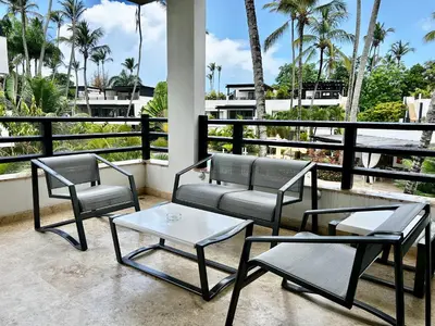 three chairs and a table on a balcony with palm trees at Beachfront complex 3BD 3BA with pool in Las Terrenas