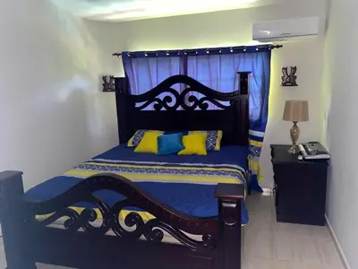 a bedroom with a bed with blue and yellow pillows at My home in San Felipe de Puerto Plata