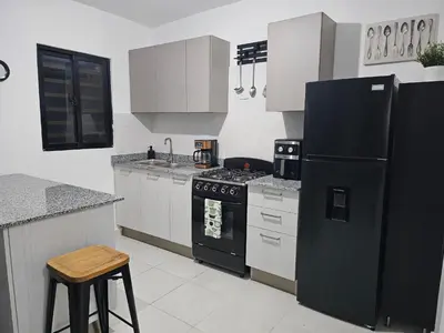 a kitchen with a black refrigerator and white cabinets at Santo Domingo Este in Ensanche Savica de Mendoza