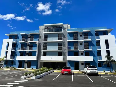 a large apartment building with two cars parked in a parking lot at Santo Domingo Este in Ensanche Savica de Mendoza