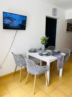 a white table with chairs and a tv on a wall at Apartamento Aurora in Bayahibe