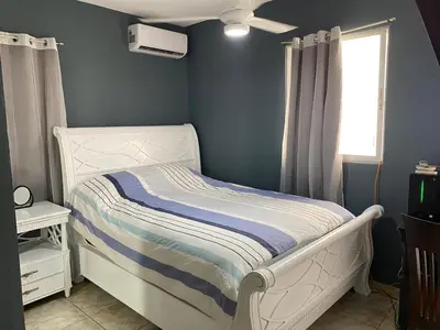 a small bedroom with a white bed and a window at Casita Azul in Isabel de Torres