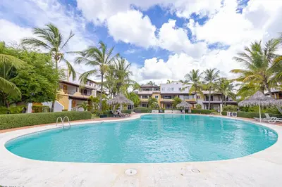 a large swimming pool with palm trees and houses at Charming 1 Bedroom in Tamarindo Dominicus With Pool in La Laguna