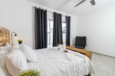 a bedroom with a large white bed and a chair at Coastal Luxury 2-Bed w Pool Access in Paraiso Bayahibe in Bayahibe