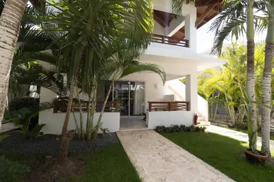 a house with palm trees in front of it at Coastal Luxury 2-Bed w Pool Access in Paraiso Bayahibe in Bayahibe