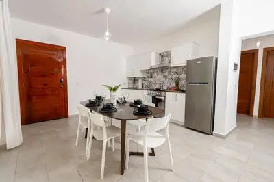 a kitchen with a table and chairs and a refrigerator at Coastal Luxury 2-Bed w Pool Access in Paraiso Bayahibe in Bayahibe