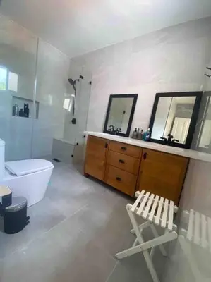 a bathroom with a tub and a toilet and a chair at Hermosa villa en metro country club Juan dolio in Paraíso