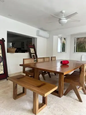a dining room with a wooden table and benches at Hermosa villa en metro country club Juan dolio in Paraíso
