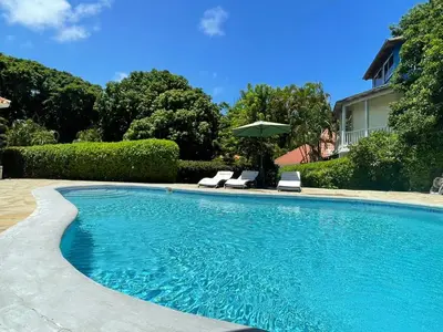 a swimming pool with two chairs and an umbrella at Villa Michel in Laguna del Higüero