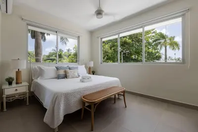 a white bedroom with a bed and two windows at Caribey 2, Las Terrenas in Las Terrenas