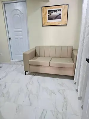 a living room with a couch in front of a door at hermoso aparta estudio a 10 minutos del centro in San Felipe de Puerto Plata