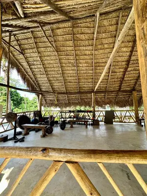 a large straw roofed room with tables and chairs at Leisy's Garden Hostel & Rooms in Santa Bárbara de Samaná
