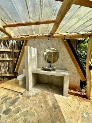 a bathroom with a sink and a mirror in a roof at Leisy's Garden Hostel & Rooms in Santa Bárbara de Samaná