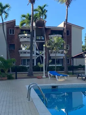 a building with palm trees and a swimming pool at Jungle Oasis by the Beach in San Felipe de Puerto Plata