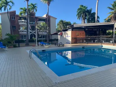 a swimming pool in front of a building with palm trees at Jungle Oasis by the Beach in San Felipe de Puerto Plata