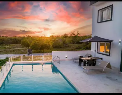 a house with a swimming pool with a table and an umbrella at CGM BLUE 1hab in Bayahibe