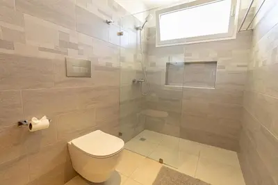 a bathroom with a toilet and a glass shower at Elegant 2 Bedroom Apartment with Pool in La Laguna