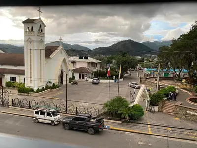 a church with cars parked in front of a street at Hotel El Parque Constanza in Constanza