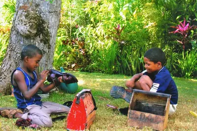 two young boys sitting in the grass under a tree at Casa Por Que No in Las Galeras