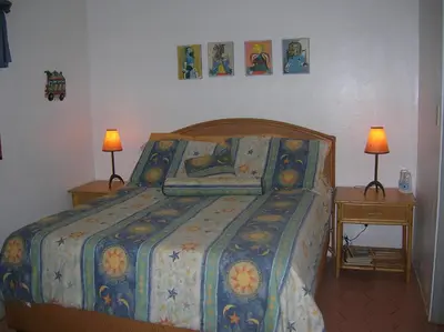 a bed with a colorful comforter and two tables with lamps at Casa Por Que No in Las Galeras
